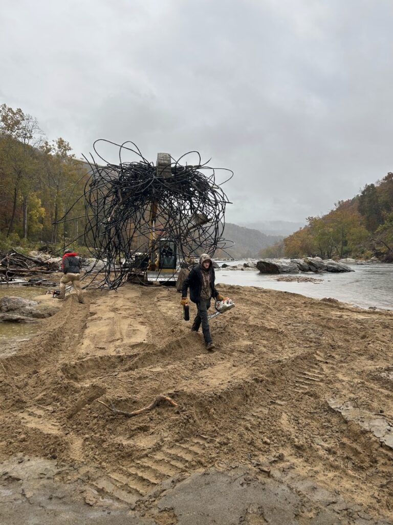 Excavator hauls pipe at the French Broad Crossing river park.