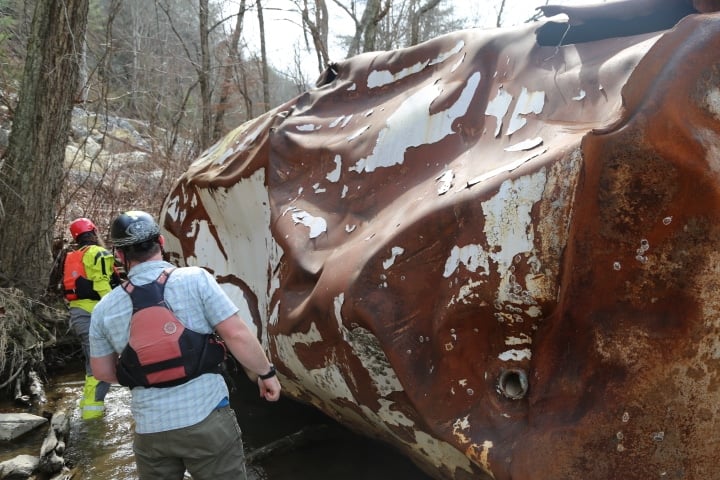 Matt Cook and Jon Stamper inspect an 11,000-pound oil tank in the river