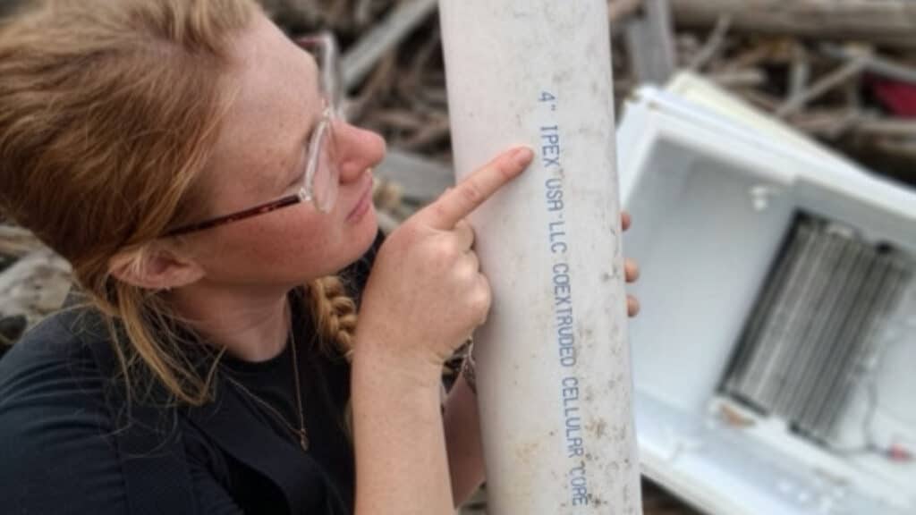 A member of MountainTrue's debris cleanup crew shows the IPEX markings on a plastic PVC pipe pulled from the French Broad River in North Carolina.