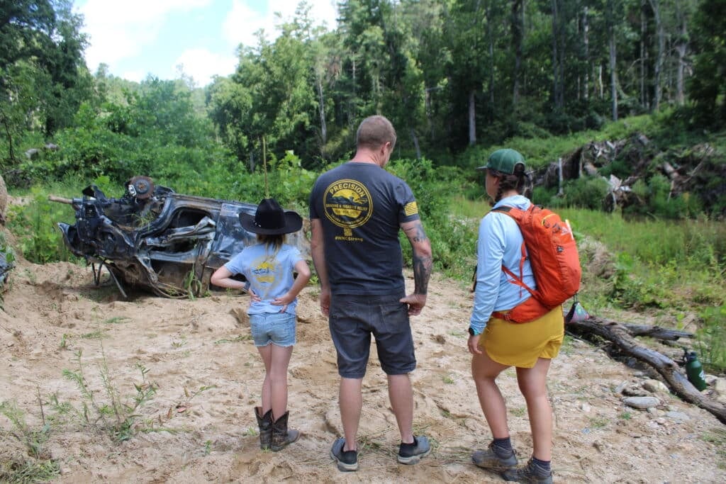 Jake Jarvis, center, and MountainTrue's Erica Shanks, right, discuss how to best remove a car from the banks of the Big Hungry River as Jarvis' daughter, Mya, surveys the debris.  Photo by Liz McGuirl